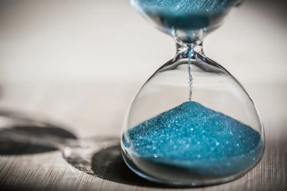 effects of steroid injections and how long they last shown by an hour glass held in a man's hand with blue sand running through it