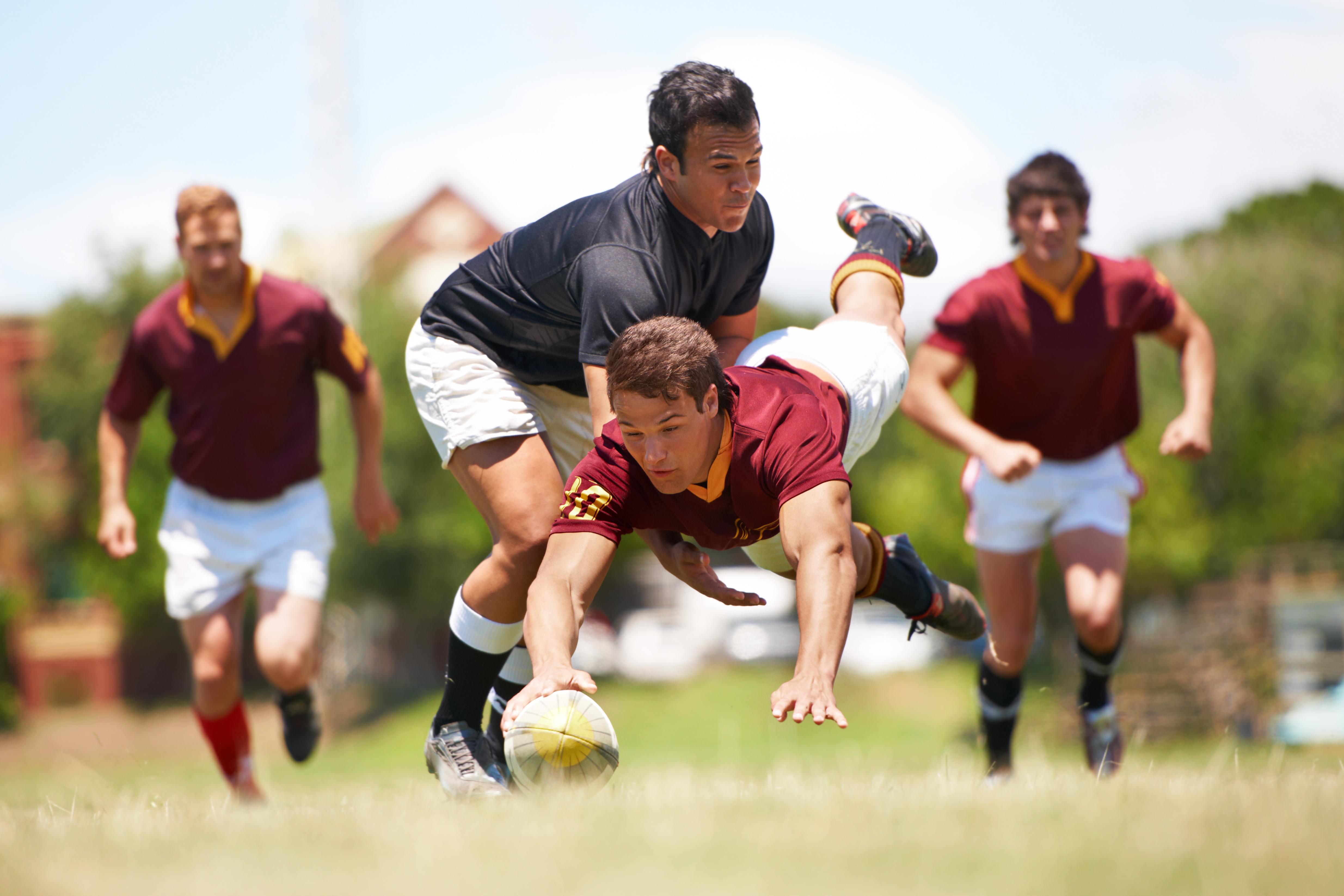 acromioclavicular joint injection - a group of men playing rugby with one player fully horizontal as he dives for the line with hand outstretched to place the ball