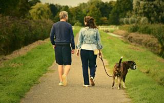 PRP for osteoarthritis of the knee - A young couple with a dog walking in a park away from the camera