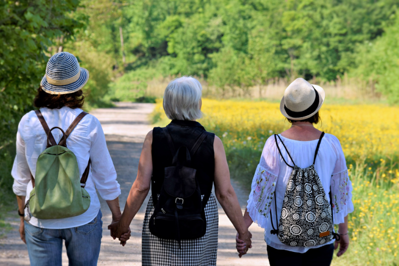 PRP for osteoarthritis of the knee - Three seniour women holding hands walking away from the camera in summer through a park