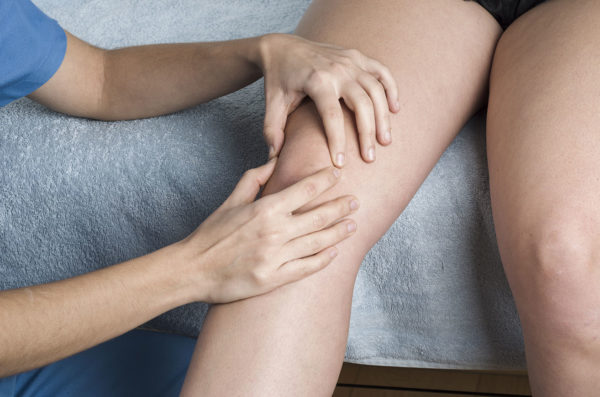 patella tendinopathy - physio feeling patient's knee with pain around the kneecap